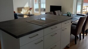 A modern kitchen with a central island, white cabinetry, and a stainless steel range hood.