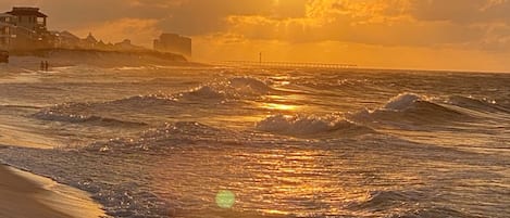 A beach with waves and a sunset.