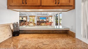 Una cocina con encimeras de granito, armarios de madera y un comedor con televisor.