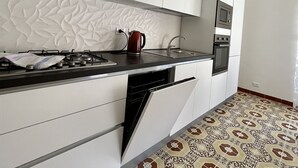 A modern kitchen with white cabinetry, a gas stove, a dishwasher, and a microwave.