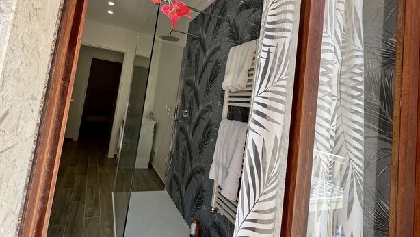 A modern bathroom with a shower, a towel rack, and a visible toilet.