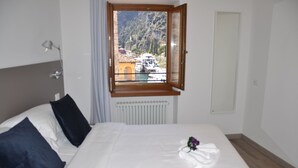 Ein Hotelzimmer mit Bett, Fenster mit Blick auf Boote und einen Berg sowie einer Heizung.