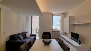 Ein modernes Wohnzimmer mit einer Couch, einem Esstisch und einem Fernseher.