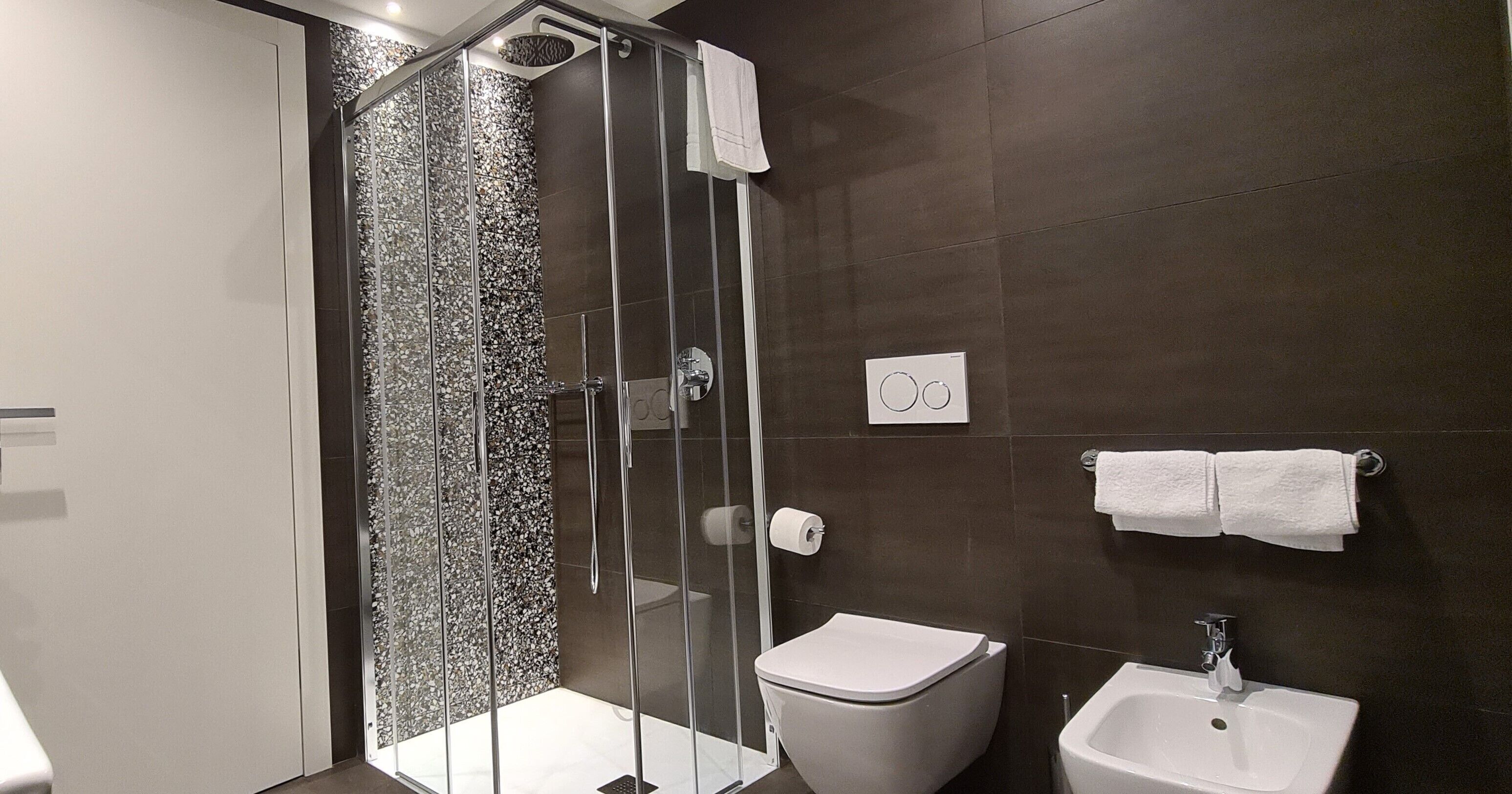 Une salle de bain moderne avec une douche à parois de verre, des toilettes blanches et un lavabo avec un miroir.