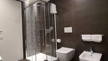 Une salle de bain moderne avec une douche à parois de verre, des toilettes blanches et un lavabo avec un miroir.
