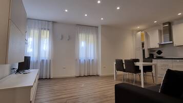 Un apartamento moderno con comedor, cocina y sala de estar con televisor.
