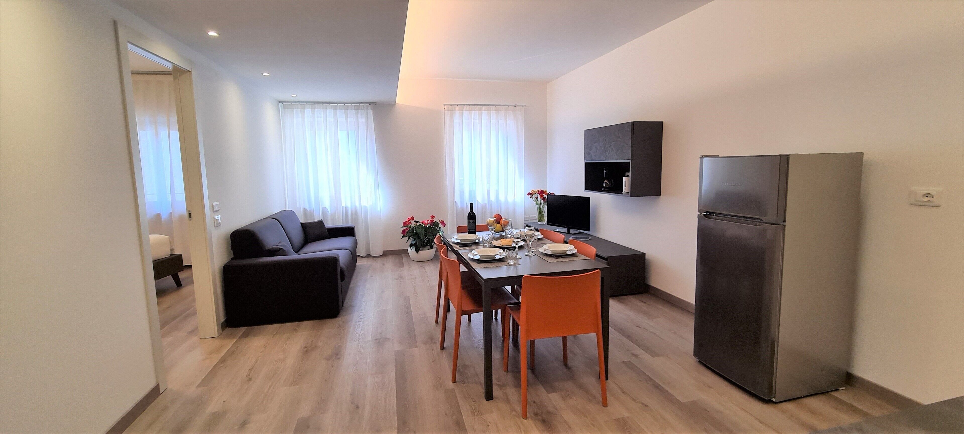 Et moderne køkken med spiseplads, et køleskab og en sofa.
