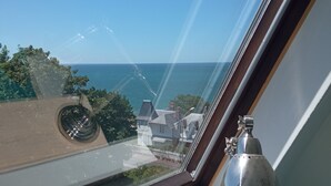 Ein Oberlichtfenster mit Blick auf das Meer und Häuser.
