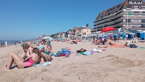 Ein Strand mit Menschen, die sich sonnen und entspannen. Sonnenschirme und Liegestühle sind vorhanden.