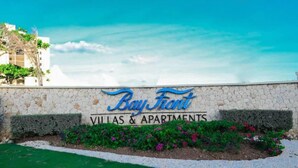 A sign for 'Bay Front Villas & Apartments' with a stone wall and greenery in front. - Ornella Villa - 2-br Apartment - Pool - Parking (Portmore)
