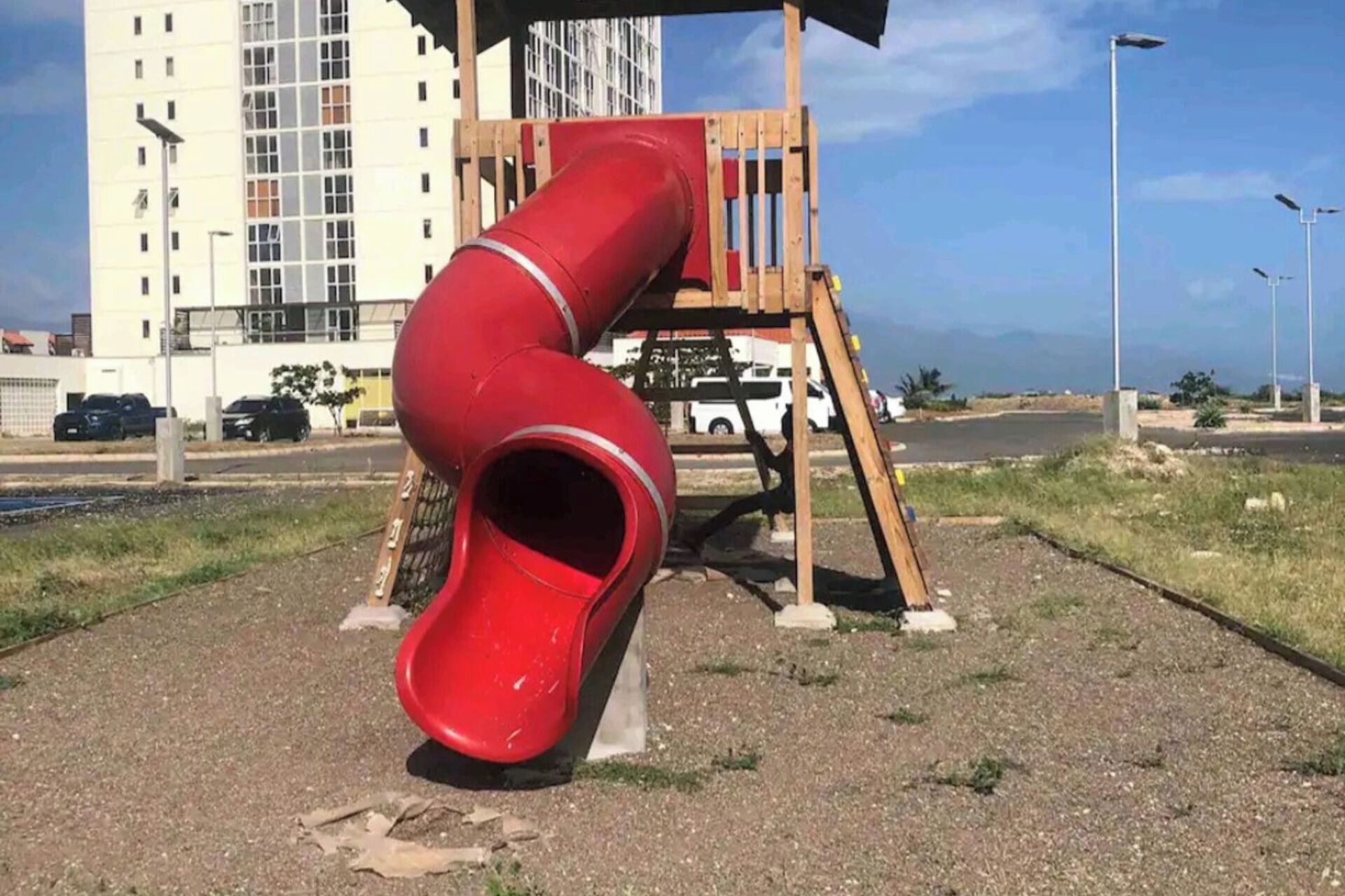 Un parque infantil con un tobogán rojo y una estructura de madera.