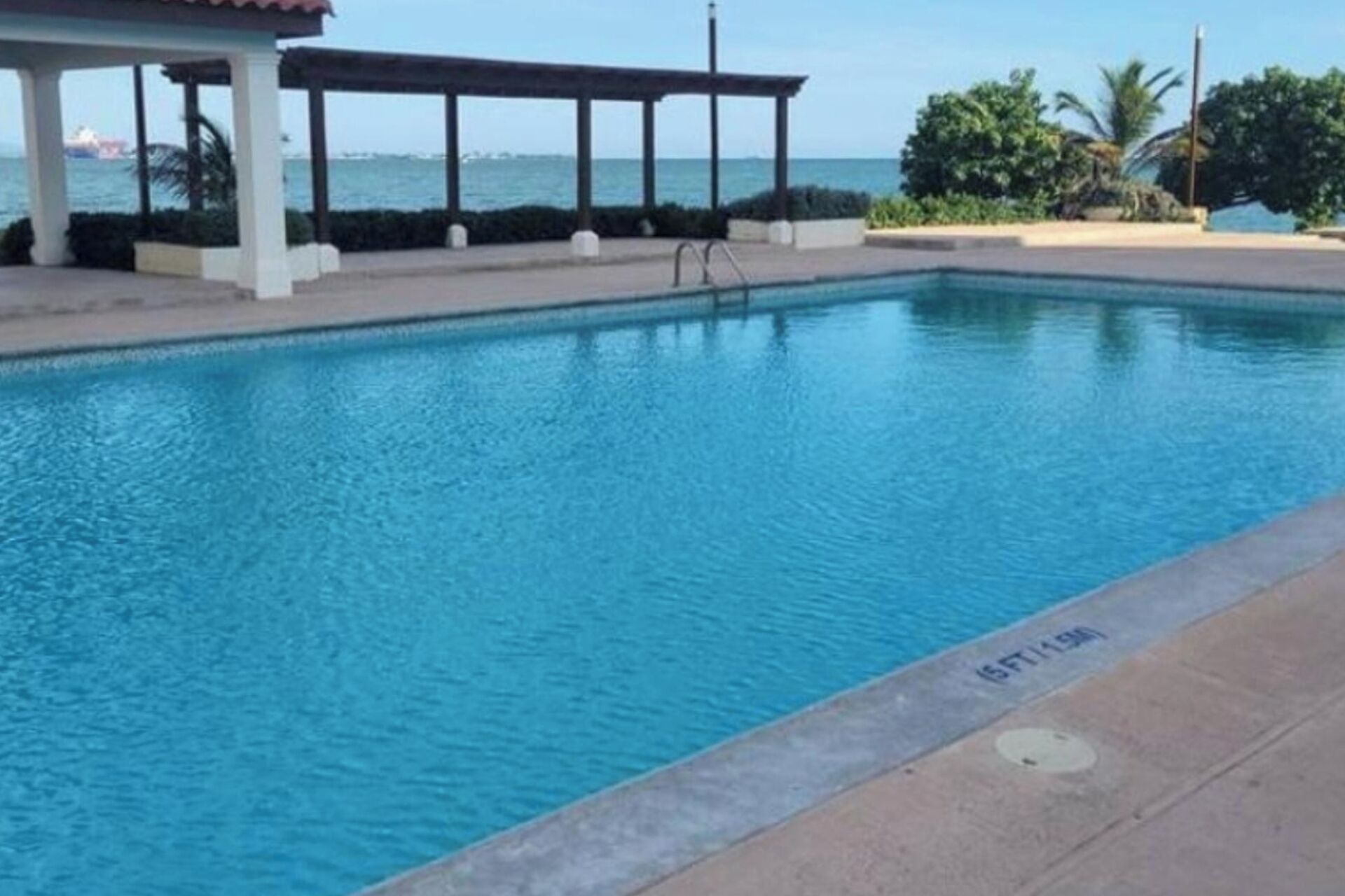 A swimming pool with a clear view of the ocean in the background.