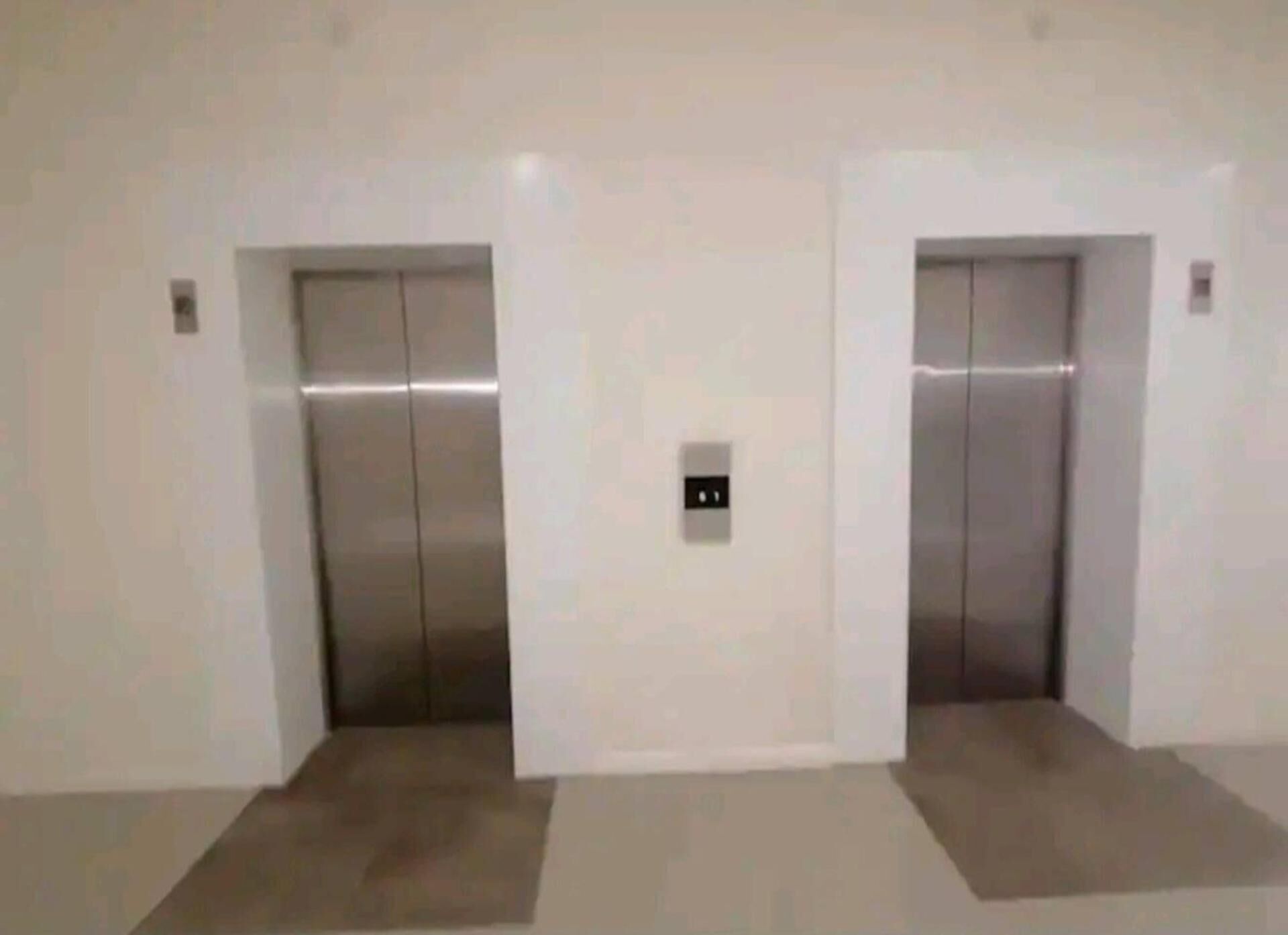 Two elevators in a hallway with a light-colored floor.