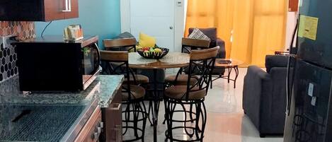 Una cocina moderna con comedor, que incluye una encimera de granito, electrodomésticos de acero inoxidable y una mesa con sillas.