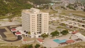 A high-rise hotel with multiple floors, a swimming pool, and a parking area. - Ornella Villa - 2-br Apartment - Pool - Parking (Portmore)