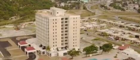 A high-rise hotel with multiple floors, a swimming pool, and a parking area.