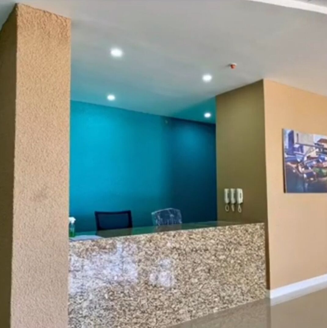A reception area with a glass counter, a chair, and a wall-mounted phone.