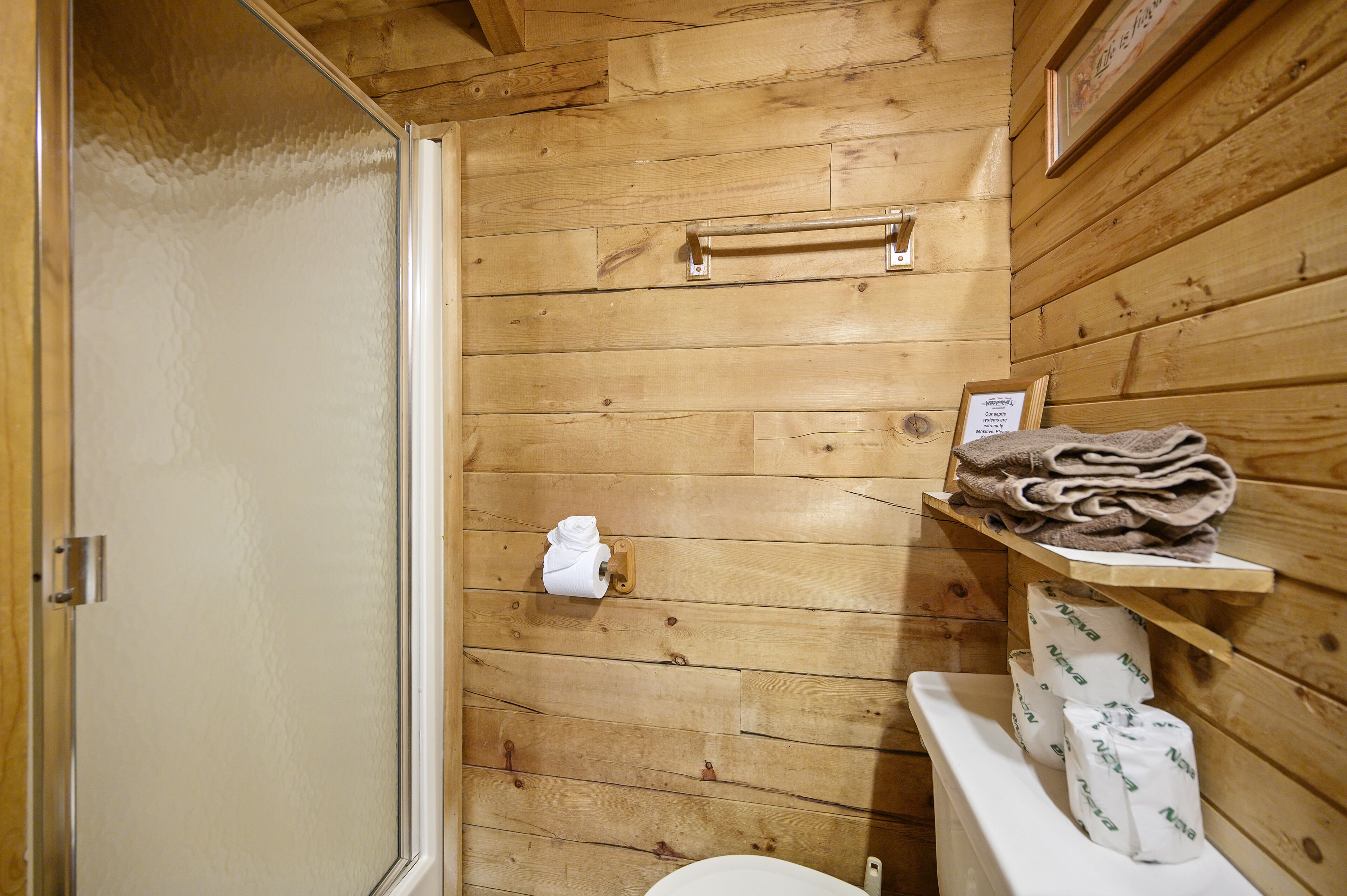 Un bagno in una cabina di legno con il water, un portasciugamani e una doccia.