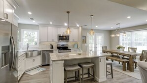 Una cocina moderna con gabinetes blancos, electrodomésticos de acero inoxidable y una isla central con taburetes de bar.