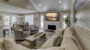 Amplia sala de estar con chimenea, asientos confortables, televisor y comedor con luz natural.