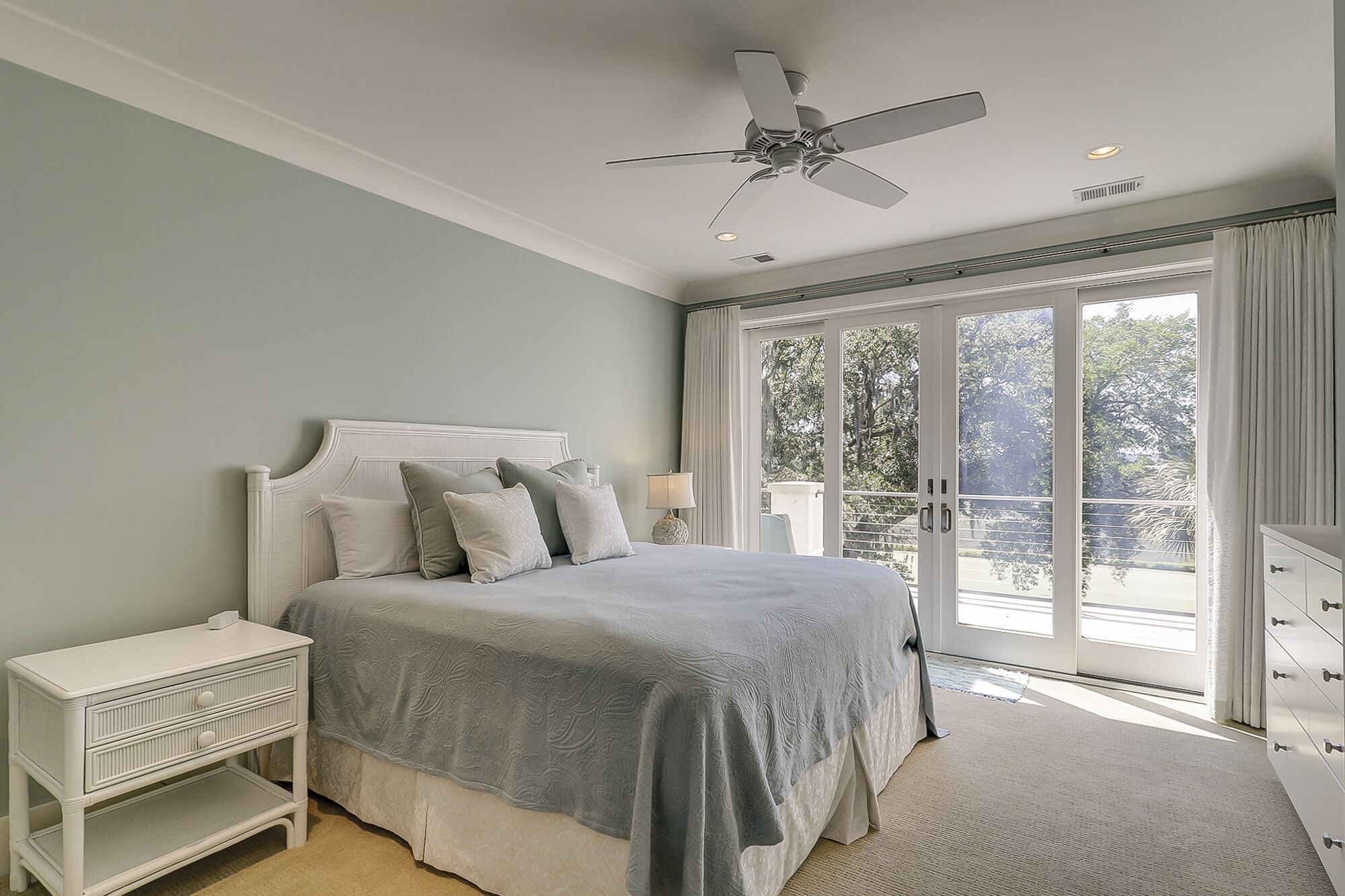 A bedroom with a bed, nightstand, dresser, and a ceiling fan.