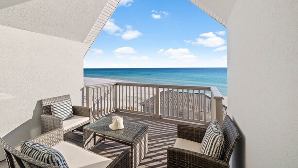 A balcony with wicker furniture, a glass table, and a view of the beach and ocean. - Gulf Views with Pool, Firepit and LSV (Santa Rosa Beach)