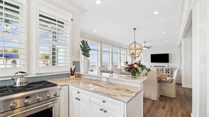 A modern kitchen with white cabinetry, a marble countertop, and a large island. - Gulf Views with Pool, Firepit and LSV (Santa Rosa Beach)
