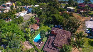 Vista aérea de una zona residencial con casas, una piscina y una playa al fondo.