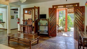 Amplia sala de estar con un banco de madera, un televisor y una estantería.