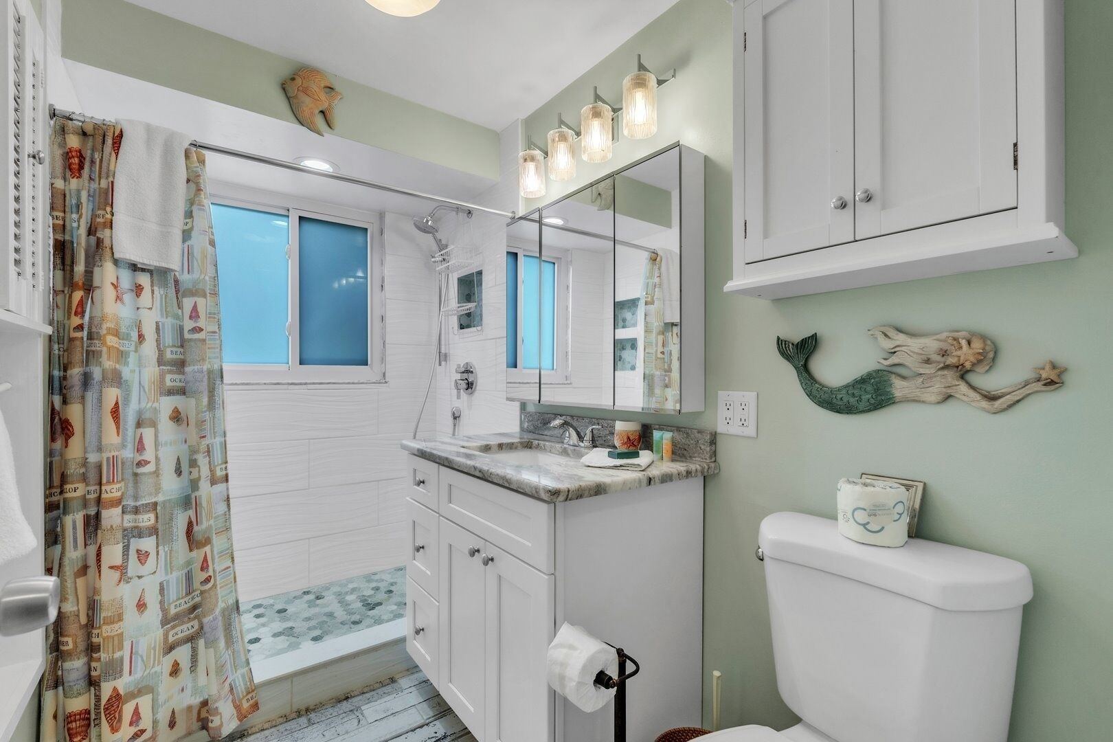 A bathroom with a shower, a sink, a toilet, and a mirror.