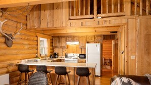 L’intérieur d’une cabane en rondins comprend une cuisine, un coin repas et un espace de vie chaleureux.