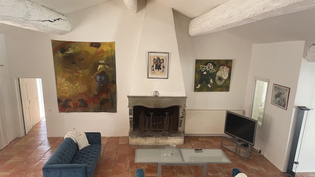 Ein Wohnzimmer mit Kamin, zwei blaue Sofas, einem Glastisch und Kunstwerken an den Wänden.
