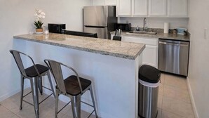 A modern kitchen with white cabinets, stainless steel appliances, and a granite countertop. - Tiki 1 Bedroom Home by RedAwning (South Padre Island)