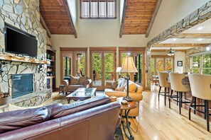 A spacious living area with a stone fireplace, leather sofa, and a dining area with bar stools. - Lakefront Retreat | Luxury Home with Gorgeous VIEWS & Private Dock! (Nebo)