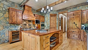 Una cocina amplia con armarios de madera, una pared decorativa de piedra y una isla grande con cajones.