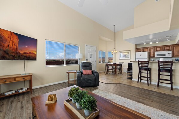 A spacious living room with a fireplace, a dining area, and a kitchen with wooden cabinets and a microwave. - About Time Oasis Mesquite Vacation Rental with Private Balcony with $510 of free daily activities (Mesquite)