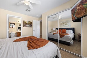 A bedroom with a large bed, a mirror, a ceiling fan, and a painting. - About Time Oasis Mesquite Vacation Rental with Private Balcony with $510 of free daily activities (Mesquite)