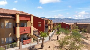 A multi-story residential building with balconies, a desert landscape, and mountains in the background. - About Time Oasis Mesquite Vacation Rental with Private Balcony with $510 of free daily activities (Mesquite)