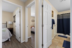 A hotel room with a bed, bedside table, lamp, and a bathroom with a shower curtain. - About Time Oasis Mesquite Vacation Rental with Private Balcony with $510 of free daily activities (Mesquite)