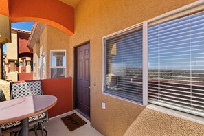 A patio area with a table and chairs, a door, and a window with blinds. - About Time Oasis Mesquite Vacation Rental with Private Balcony with $510 of free daily activities (Mesquite)