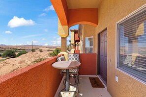A balcony with a table and chairs, a door, and a view of the desert landscape. - About Time Oasis Mesquite Vacation Rental with Private Balcony with $510 of free daily activities (Mesquite)