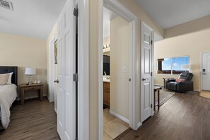 A hotel room with a bed, bedside table, lamp, and a view of the hallway. - About Time Oasis Mesquite Vacation Rental with Private Balcony with $510 of free daily activities (Mesquite)