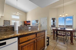 A kitchen with granite countertops, wooden cabinets, a dining area with a table and chairs, and a ceiling fan. - About Time Oasis Mesquite Vacation Rental with Private Balcony with $510 of free daily activities (Mesquite)