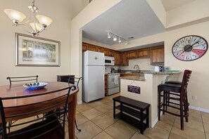 A kitchen with wooden cabinets, a white refrigerator, a microwave, and a clock on the wall. - About Time Oasis Mesquite Vacation Rental with Private Balcony with $510 of free daily activities (Mesquite)