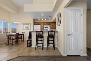 A kitchen with wooden cabinets, a refrigerator, a microwave, and a clock on the wall. - About Time Oasis Mesquite Vacation Rental with Private Balcony with $510 of free daily activities (Mesquite)