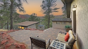 A patio with a stone floor, a chair, a table, and a small shed. - Walk to Trails! Red Rock Views! Pet Friendly! (Sedona)