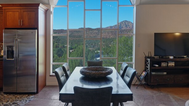 A dining area with a large window offering a view of a mountainous landscape. - Walk to Trails! Red Rock Views! Pet Friendly! (Sedona)