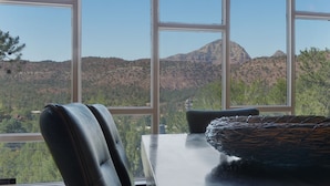 A dining area with a table and chairs, large windows offering a view of a mountainous landscape. - Walk to Trails! Red Rock Views! Pet Friendly! (Sedona)