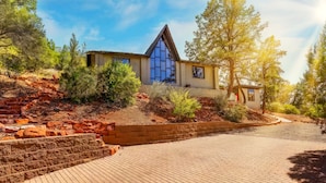 A modern house with a unique triangular roof, surrounded by trees and a paved driveway. - Walk to Trails! Red Rock Views! Pet Friendly! (Sedona)
