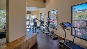 Un gimnasio en casa con cintas de correr, bicicletas estáticas y pesas.